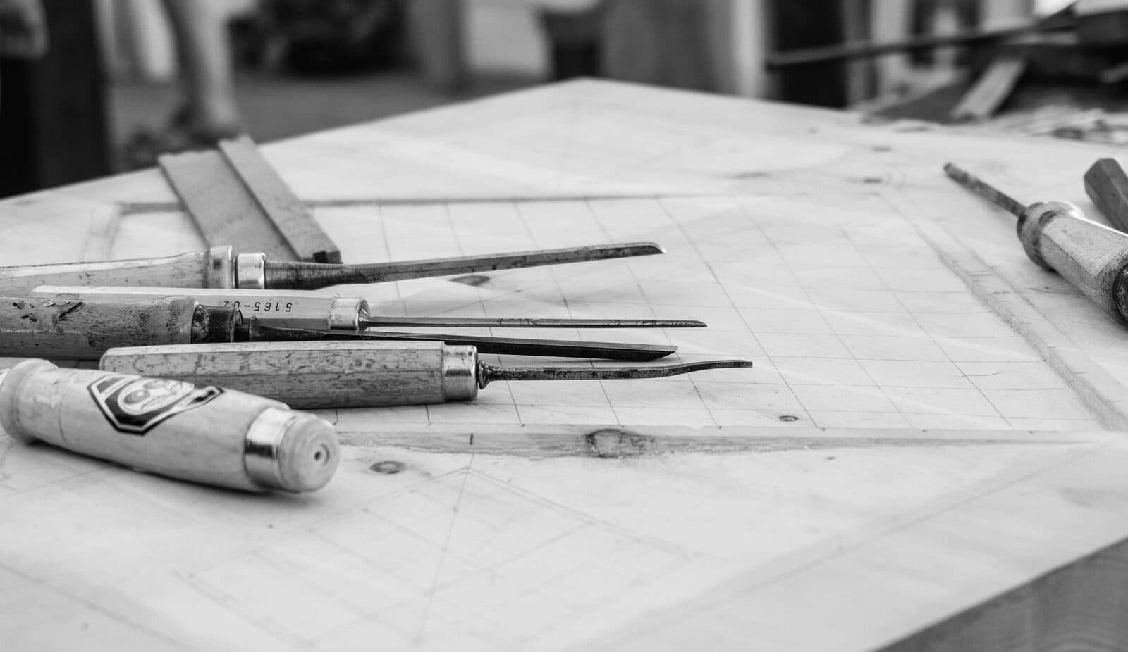 Des ciseaux à bois posés sur un établi tracé au crayon